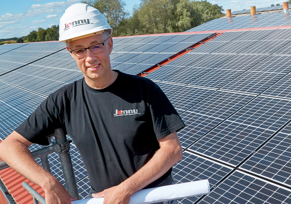 Energielösungen: eine Fachkraft für Elektrotechnik arbeitet auf einem Dach mit Solarplatten.